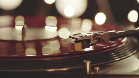 a slide turntable vinyl record player. the vinyl record on dj turntable record player close up. the stylus smoothly with a needle onto a rotating red vinyl plate. included gramophone and torque plate