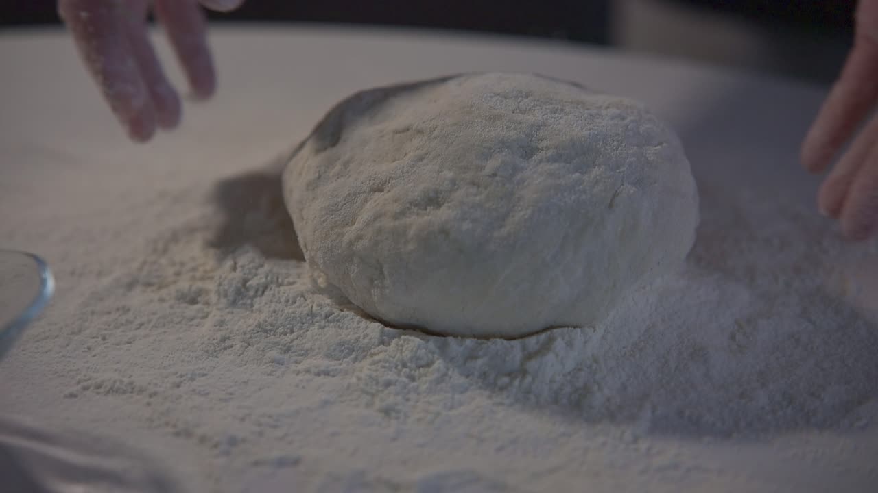 Hands Placing Fresh Dough onto a Floured Surface