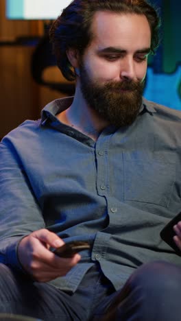 vertical video happy man holding remote control chatting on smartphone