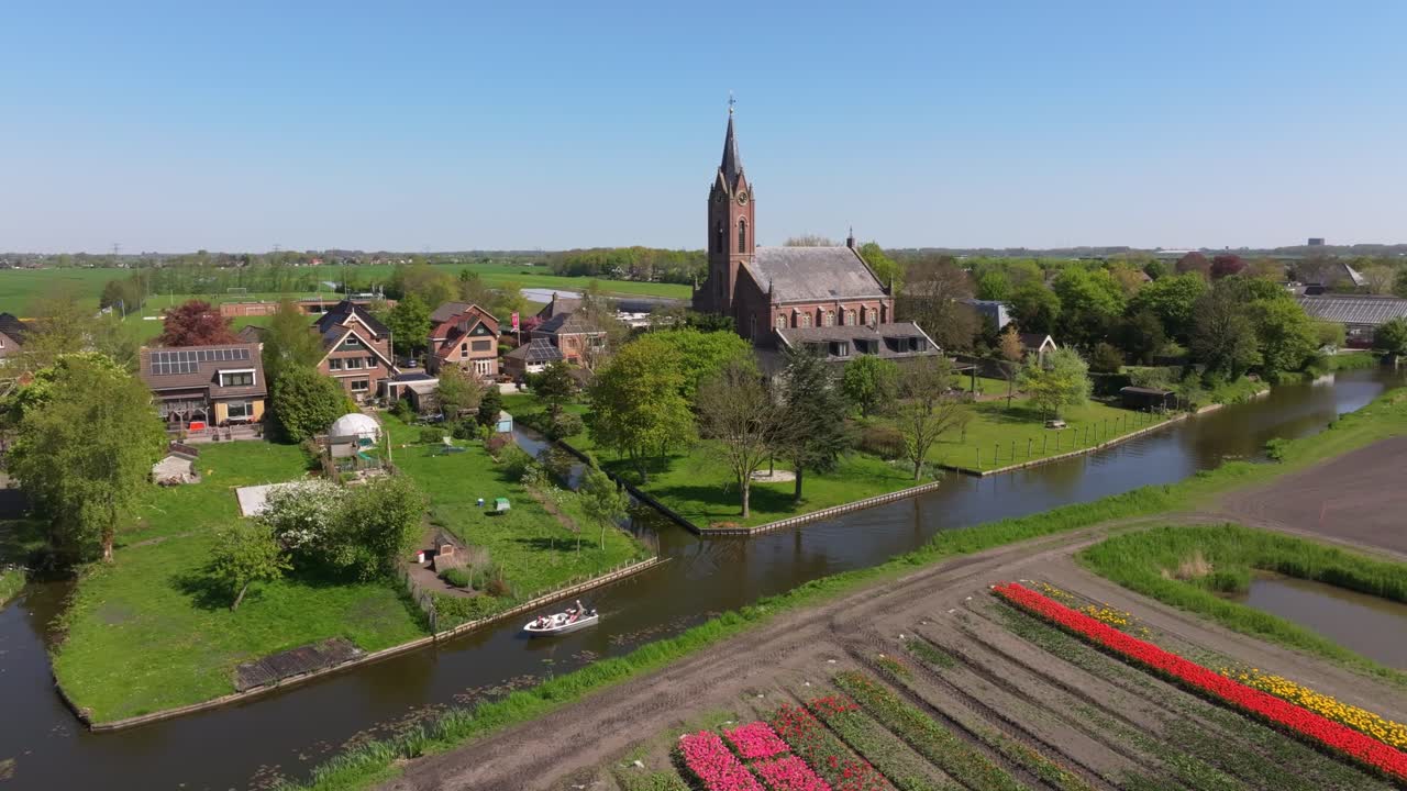 Vista aerea del villaggio olandese di Berkhout, tulipani e piccola barca sull'acqua.