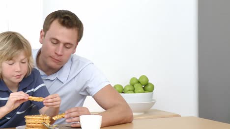 panorama de padre e hijo comiendo en la cocina