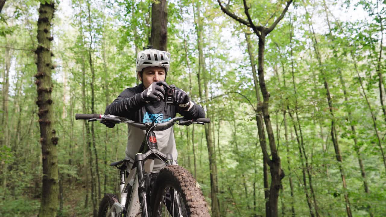 Mountain bike rider hold action camera in hands and push buttons, Czechia