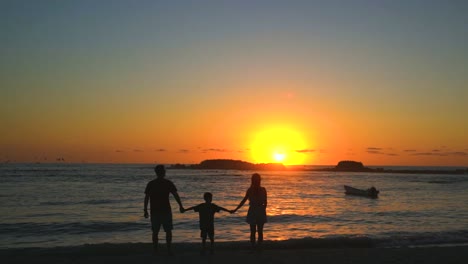 Familia-En-Vacaciones-En-La-Playa-Disfrutando-De-Una-Tranquila-Y-Relajante-Puesta-De-Sol-En-El-Océano