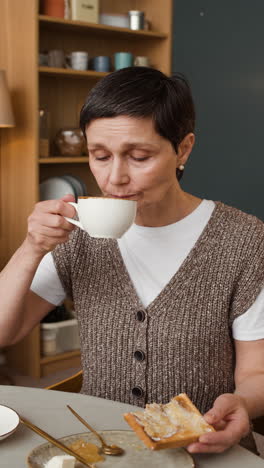 woman enjoying breakfast with toast and coffee at home
