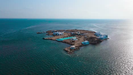 an aerial view of el biben island with a pool and hosting houses sits in the middle of the ocean with palm trees on it, surrounded by water creating a beautiful atmosphere