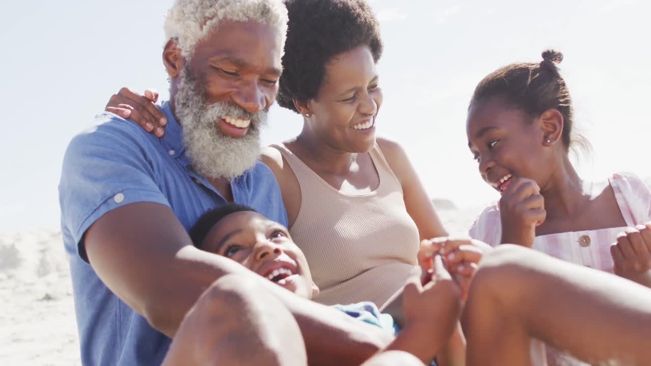 Happy african american couple embracing with children on sunny beach