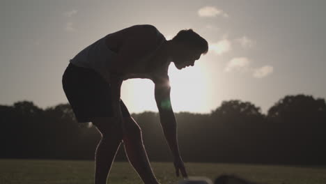 Man-Stretching-His-Legs-Before-a-Run-Whilst-Being-Silhouetted-By-The-Evening-Sun-In-Slow-Motion---Ungraded