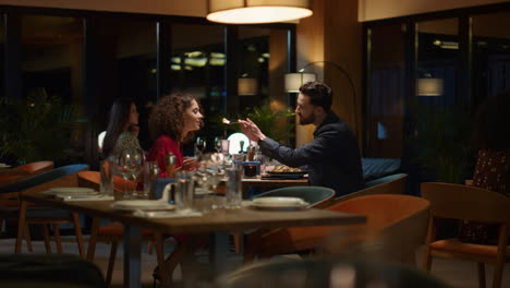 multiracial couple sharing food dinner in italian restaurant on romantic date.