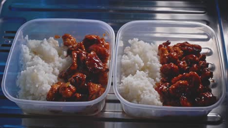 tuppers de pollo y arroz listos para comer en una cocina, vista de cerca con zoom out