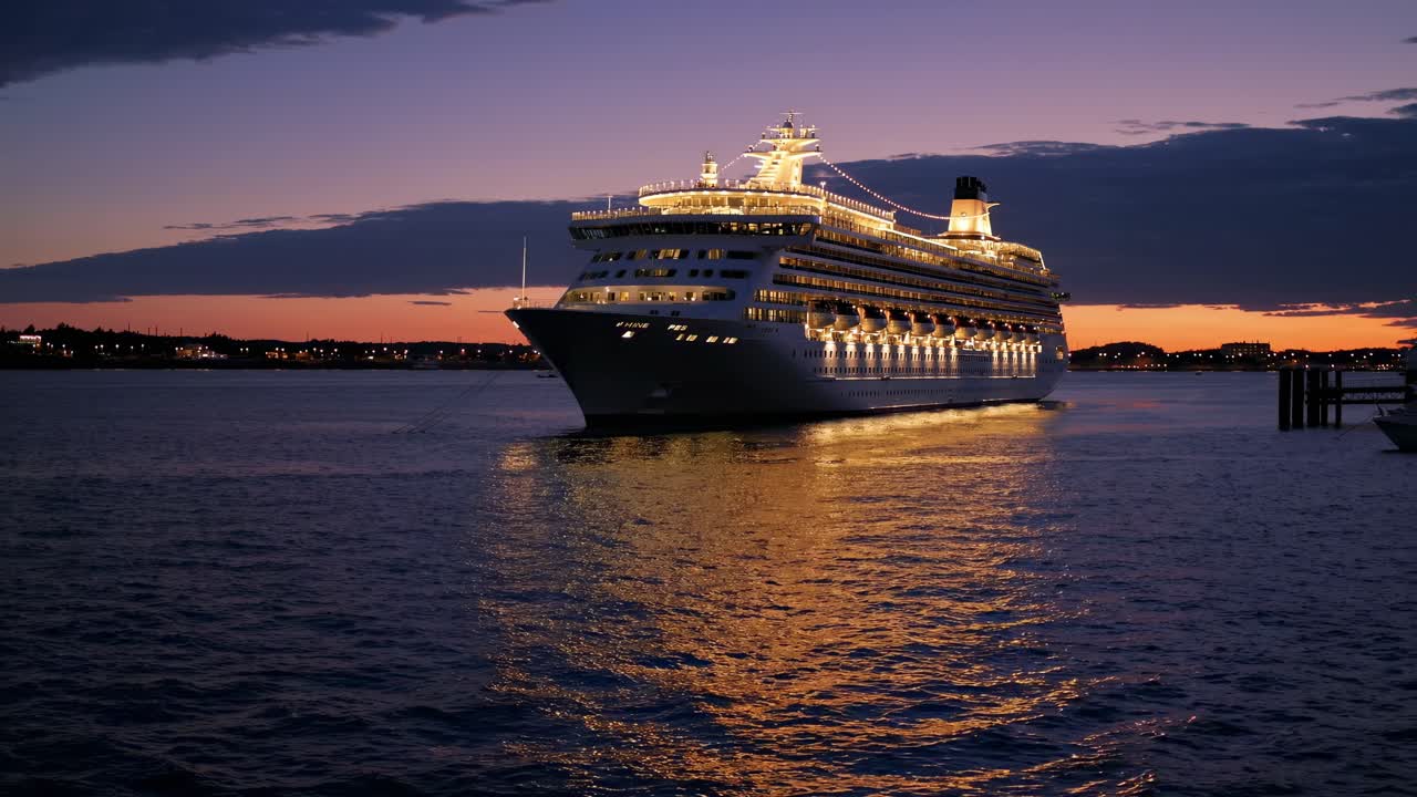 Illuminated luxury cruise liner gliding smoothly across tranquil ocean waters during twilight, casting mesmerizing reflection on glistening sea surface at sunset