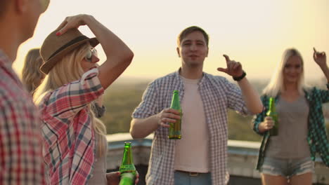 a women beautifully moves her hands in a dance. she is dancing with her friend on the roof in a hot sunny everning with beer.