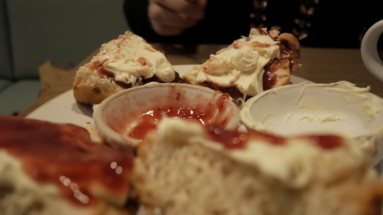 A plate of scones topped with clotted cream and jam, evoking comfort and indulgence