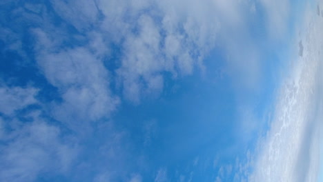 hochformat: dünne cumuluswolken ziehen im zeitraffer über den blauen himmel