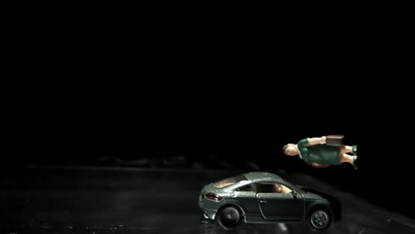 green toy car crashing into a woman figurine