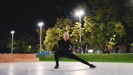 Sportive-Blond-Man-Stretching-Legs-Before-Training-In-The-Park-At-Night