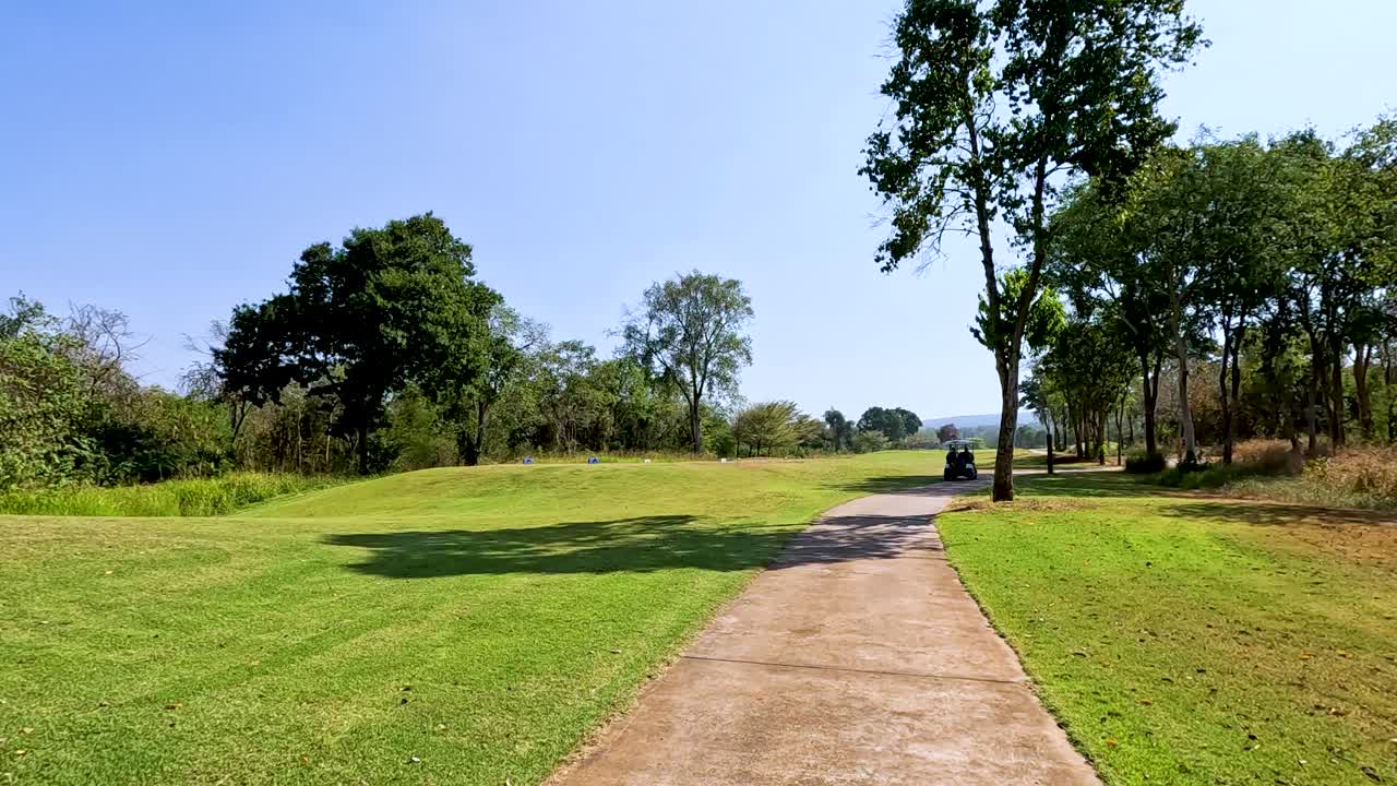 Golf cart travels through lush, green landscape