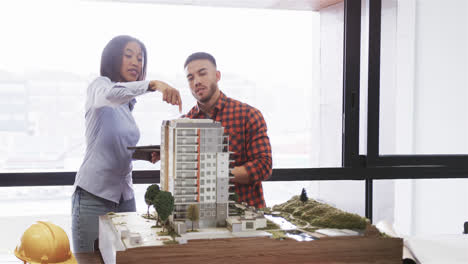 arquitecto masculino y femenino diversos discutiendo modelo arquitectónico en la oficina, cámara lenta