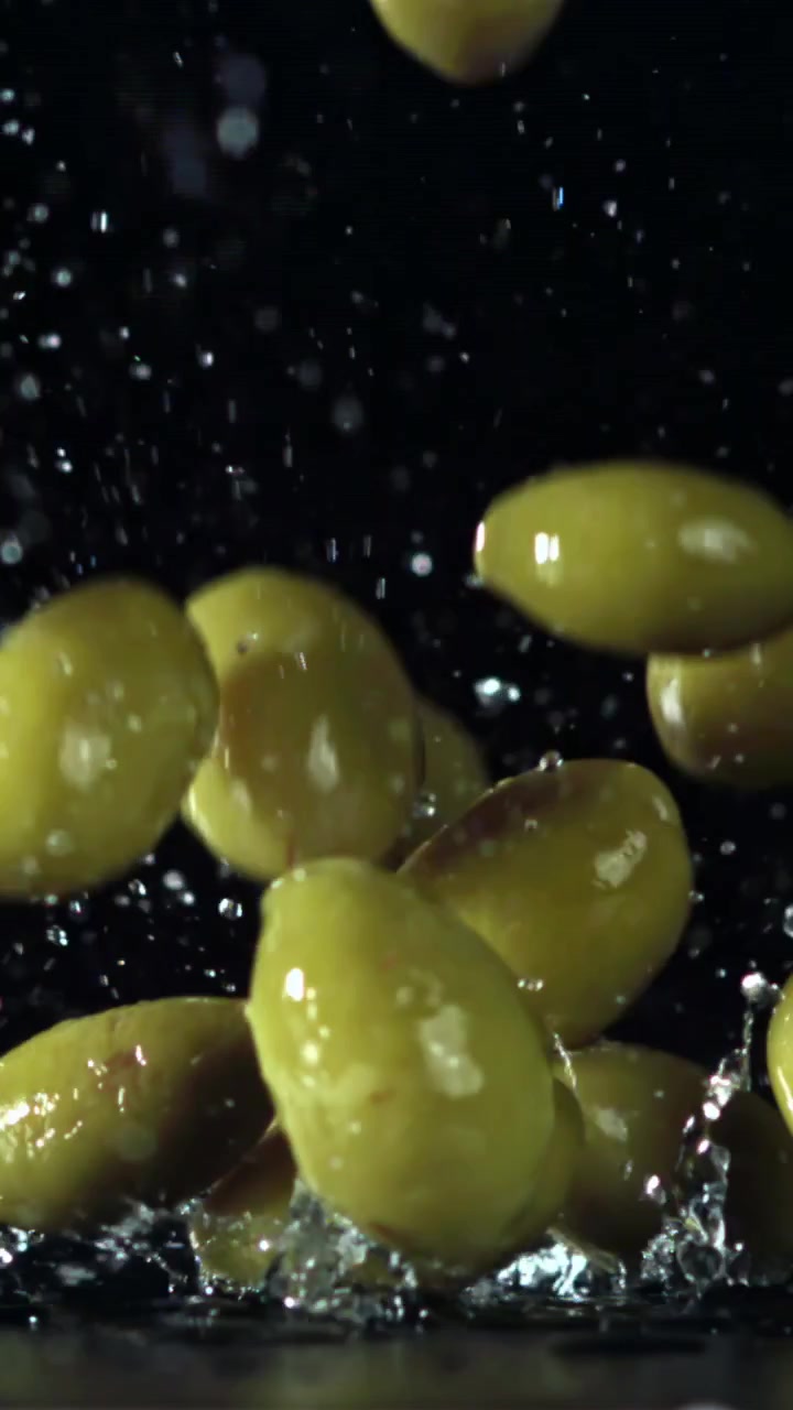 Olive verdi fresche che cadono e schizzano al rallentatore