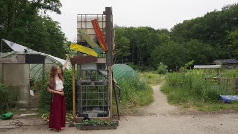 hippie ecoconsciente femenina que muestra carteles coloridos para una vida sostenible en la aldea