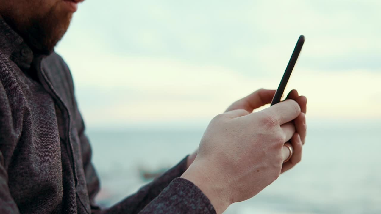 해변에서 스마트폰을 사용하는 남자