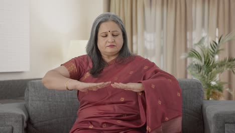 Relaxed-Indian-old-woman-doing-breathe-in-breathe-out-exercise