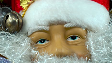 Weihnachtsmann-Spielzeug-Mit-Rotem-Hut-Und-Glöckchen,-Großer-Weißer-Bart,-Weihnachtsdekoration,-Traditionelle-Feiertagsgeschenke,-Neujahrsdekoration,-Glänzendes,-Farbenfrohes-Dekor,-Detaillierte-Nahaufnahme-Mit-Sanfter-Neigung-Nach-Unten,-4K-Video