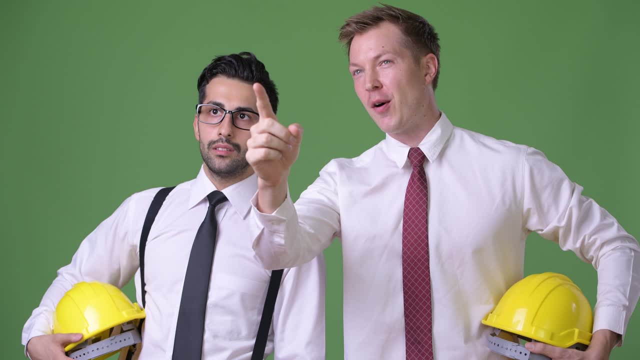 초록색 배경에서 함께 일하는 두 명의 젊은 다민족 사업가