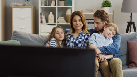 Familie-Mit-Kindern,-Die-Auf-Dem-Sofa-Im-Wohnzimmer-Sitzen-Und-Fernsehen