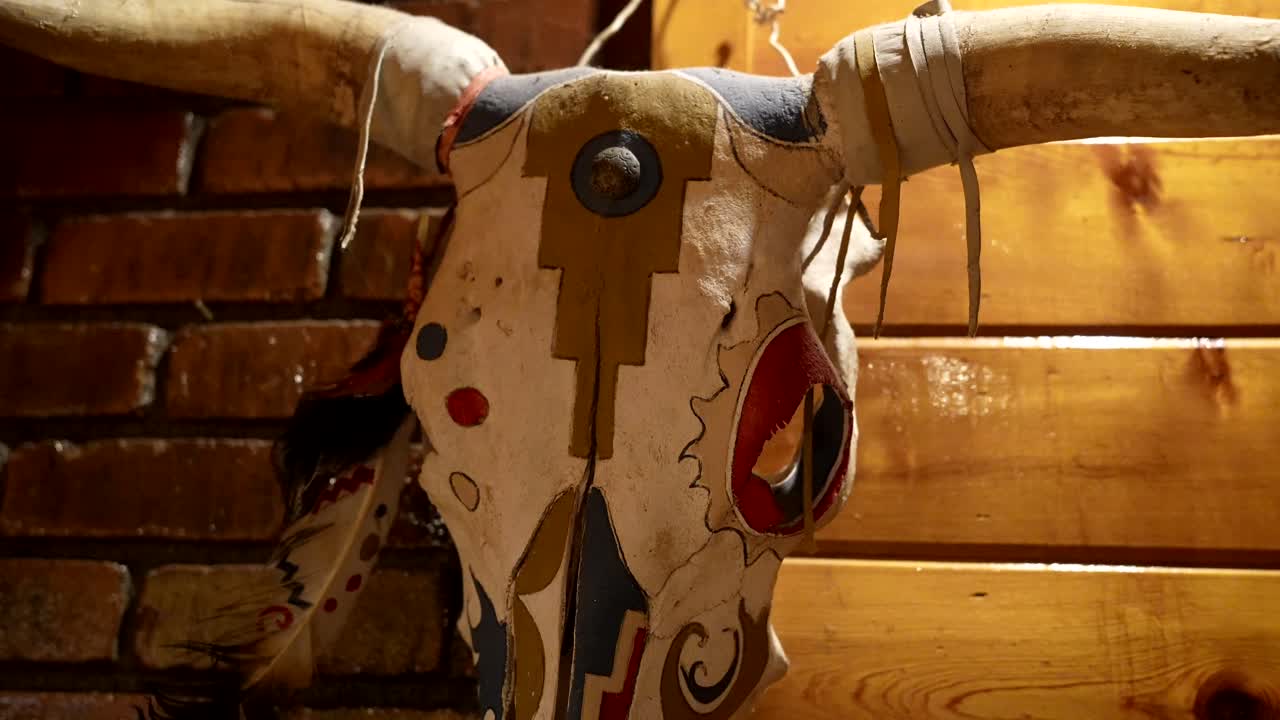 Teschio di animale decorato con arte tribale appeso a una parete rustica