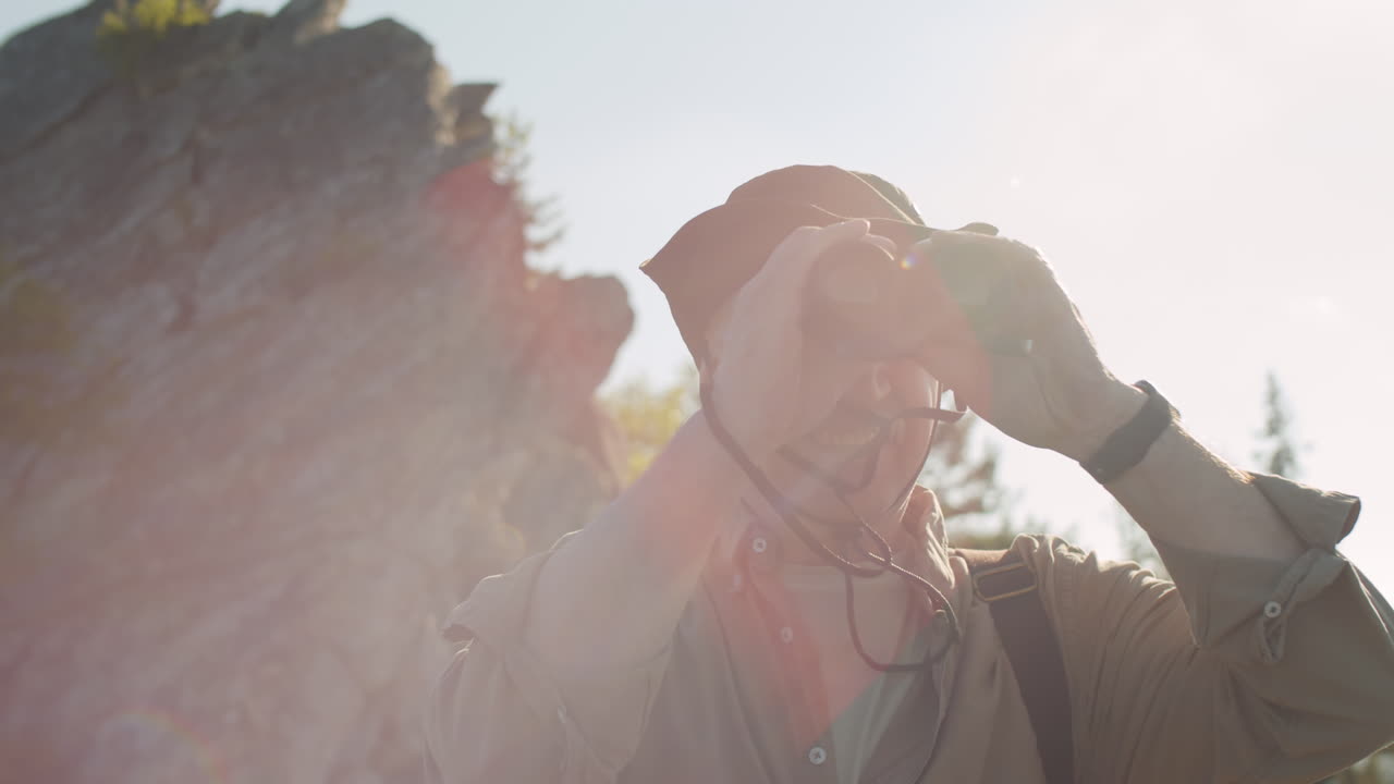 старший мужчина с биноклем в горах