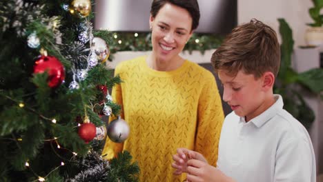 madre y hijo caucásicos felices decorando el árbol de navidad en navidad.