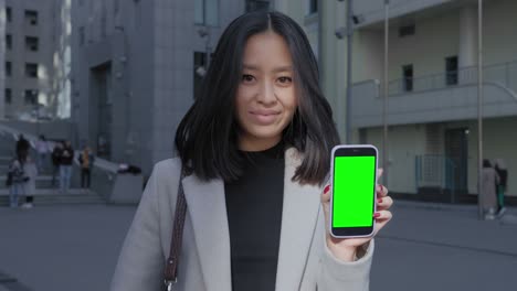 asian businesswoman holding a smart phone with a green screen chroma key