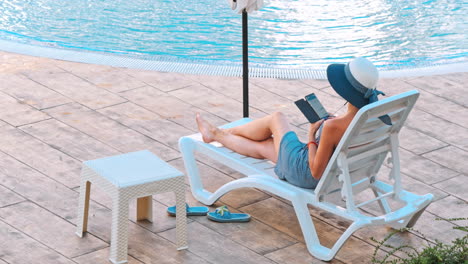 mujer tomando el sol en una silla junto a la piscina