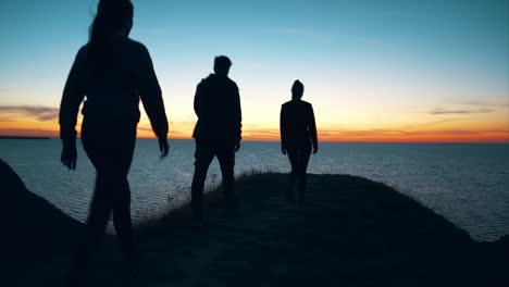 las tres personas caminando por la montaña contra el paisaje marítimo