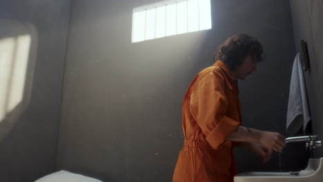 inmate washing face and using towel during morning routine in prison cell