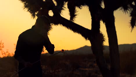side silhouette of man blowing fire in the desert at sunset