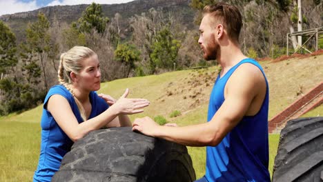 hombre y mujer en forma interactuando entre sí durante una carrera de obstáculos