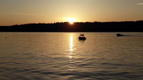 a lone motor boat slowly bobbing in the morning waves, anchored in puget sound, vashon island in the background, golden sunrise, gig harbor, washington, peaceful