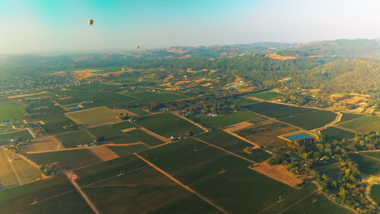 Admirable view of Napa vineyards on beautiful sunny day. Hot air balloons flying over the gorgeous valley and green mountains. Top view.