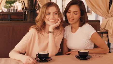 two women friends enjoying coffee at an outdoor cafe