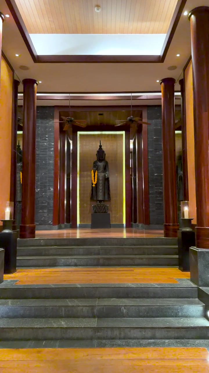 Langsom zoom mod en stående Buddha-statue i en storslået, træpanelbeklædt luksusresortkorridor