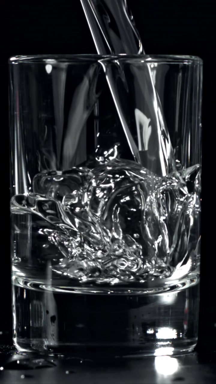 Versamento al rallentatore di acqua fresca in un bicchiere