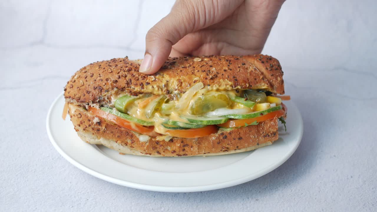 la mano sosteniendo un sándwich fresco y saludable de verduras