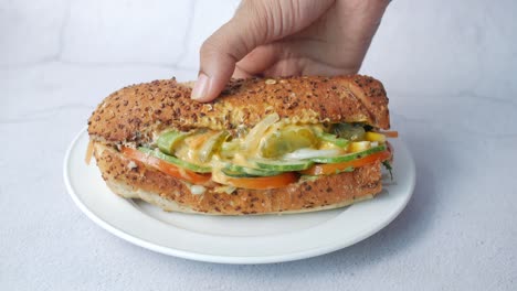 hand holding a fresh, healthy veggie sub sandwich