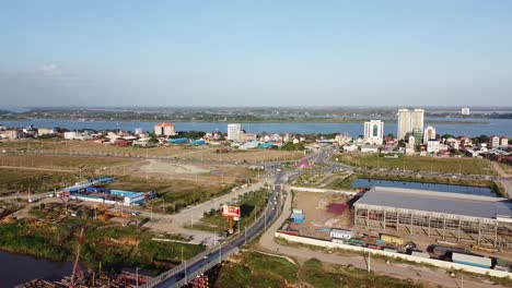 Toma-Panorámica-Estática-Aérea-Del-Tráfico-En-La-Carretera-Y-El-Río-Mekong-En-Segundo-Plano-En-Un-Día-Soleado,-Camboya