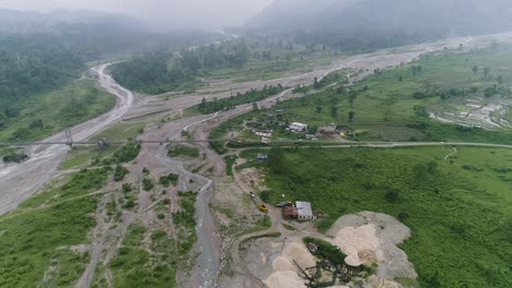 bridge over river runs through the valleys with lush vegetation surrounded by mountains hidden by fog