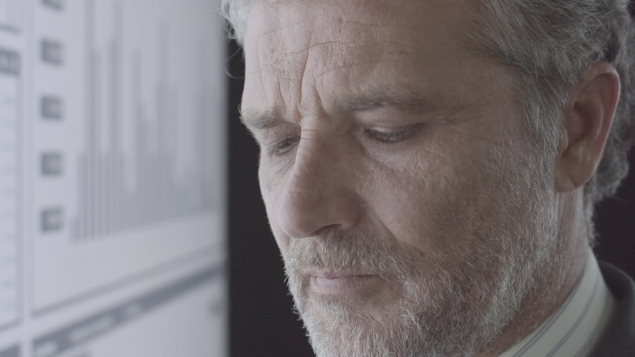 Focused mature investor analyzing financial trading charts