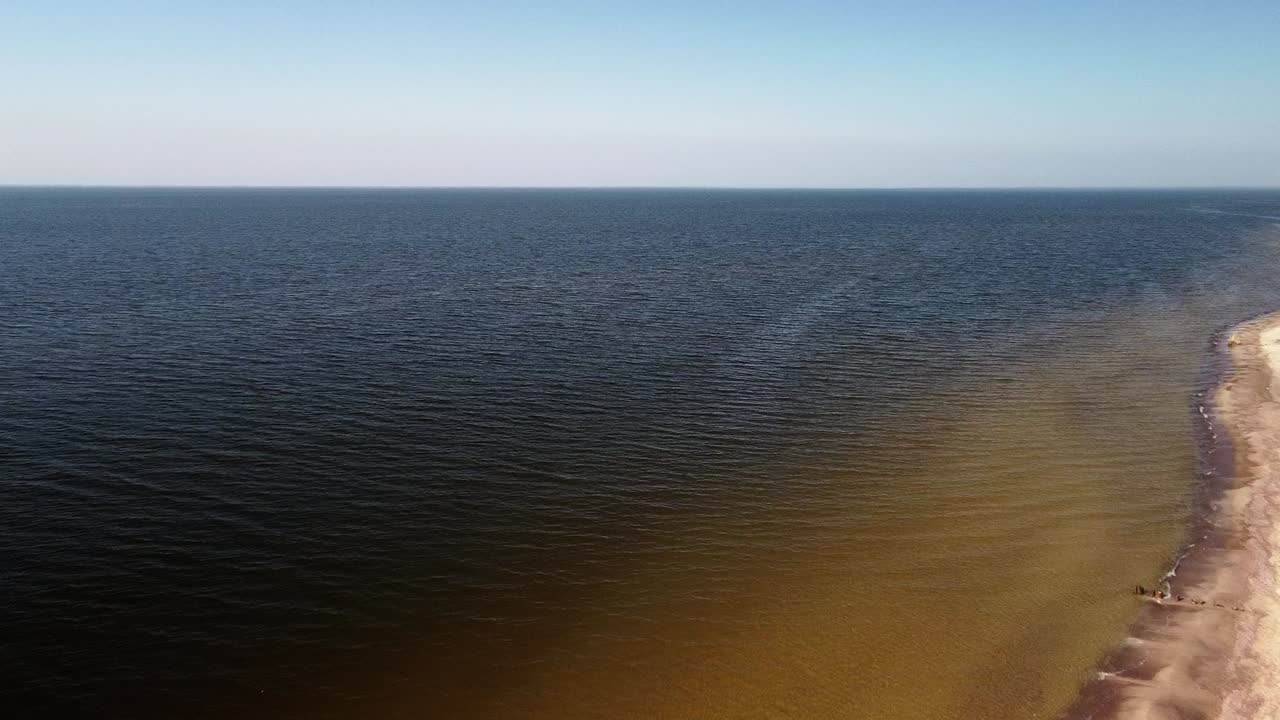 화창한 봄날, 발트해, 파페 해변, 라트비아, 광각 드론 샷이 앞으로 나아가는 하얀 모래와 함께 해변에 충돌하는 바다 파도의 공중 높은 전망