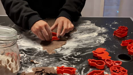 cutting out christmas gingerbread cookies from raw, rolled dough