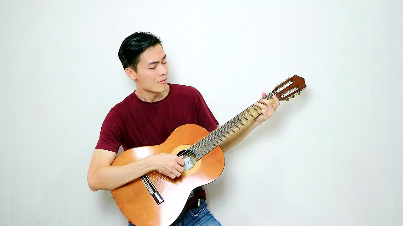 그의 오래된 어쿠스틱 기타에서 핑거스타일을 연주하는 아시아 남자